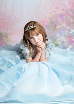 a girl rests her head on her hands while wearing a blue princess dress
