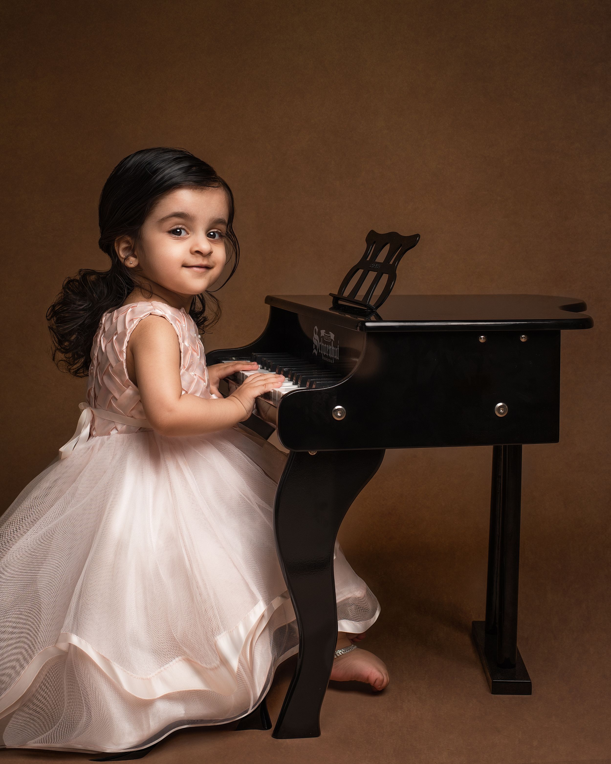 a young girl plays a tiny piano in a studio with a minneapolis photographer
