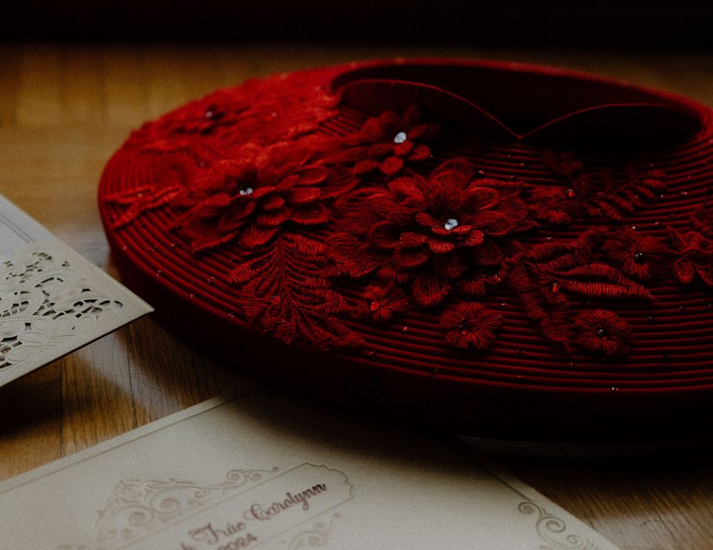 A vintage red velvet beret with delicate beading detail rests beside sheet music on a wooden surface.
