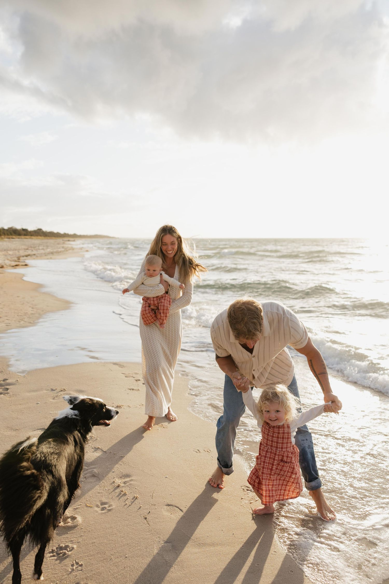 Family enjoying a playful moment together on a grassy hillside during golden hour.
