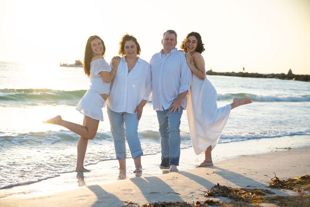 Family group enjoying a carefree moment walking together on a sunny beach at sunset.
