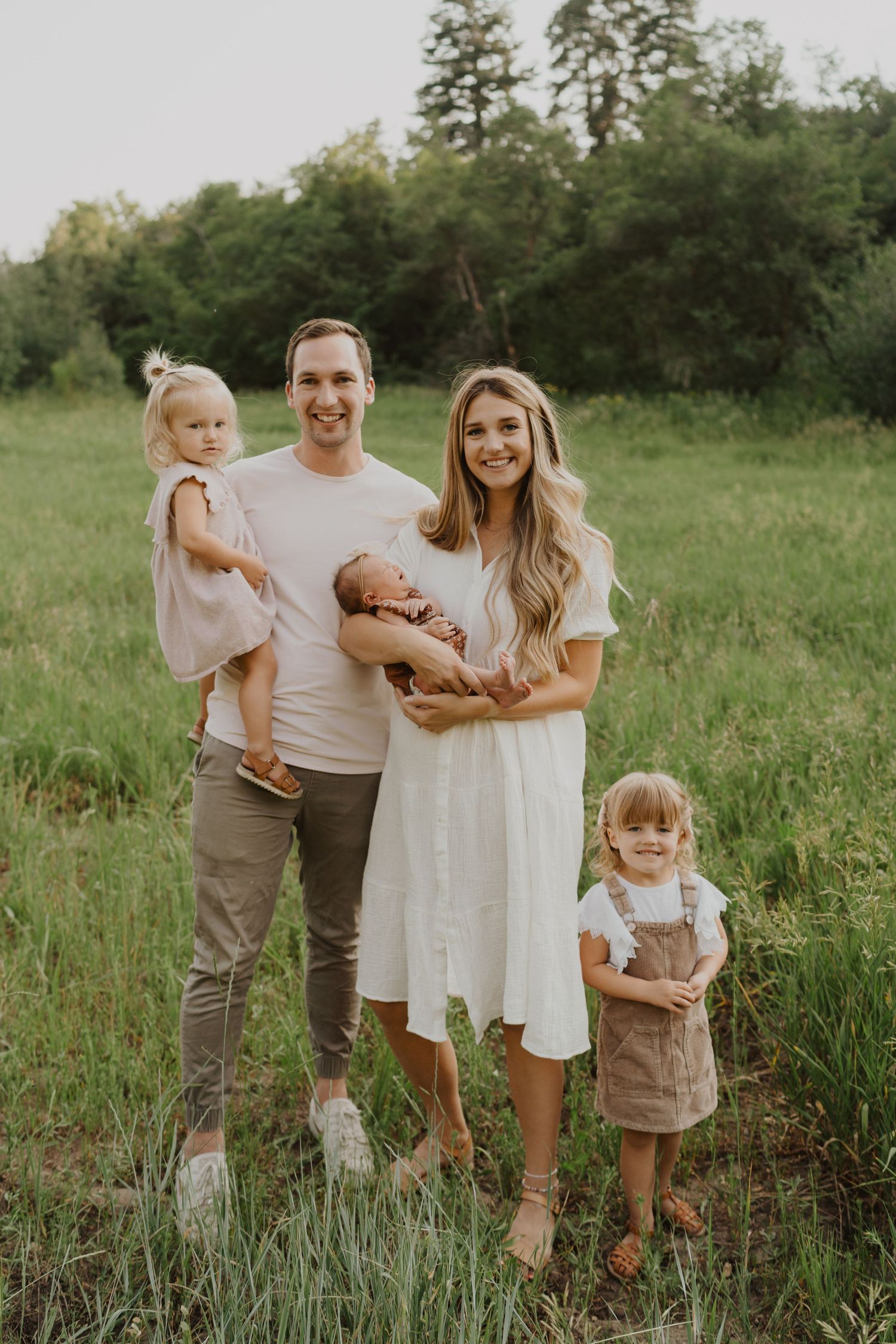 Family portrait in a green meadow with young children at sunset.