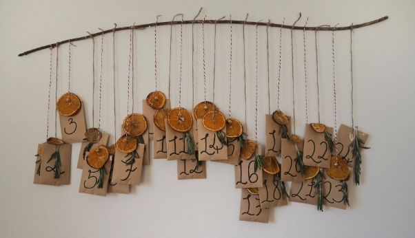 A rustic advent calendar made with numbered tags hanging from a branch with twine.
