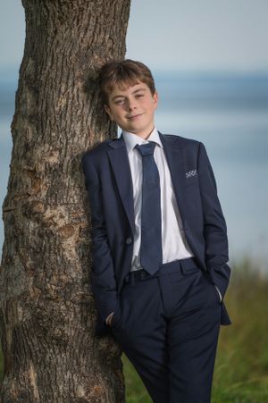 Outdoor portrait series against a tree trunk with navy suit and natural backdrop.