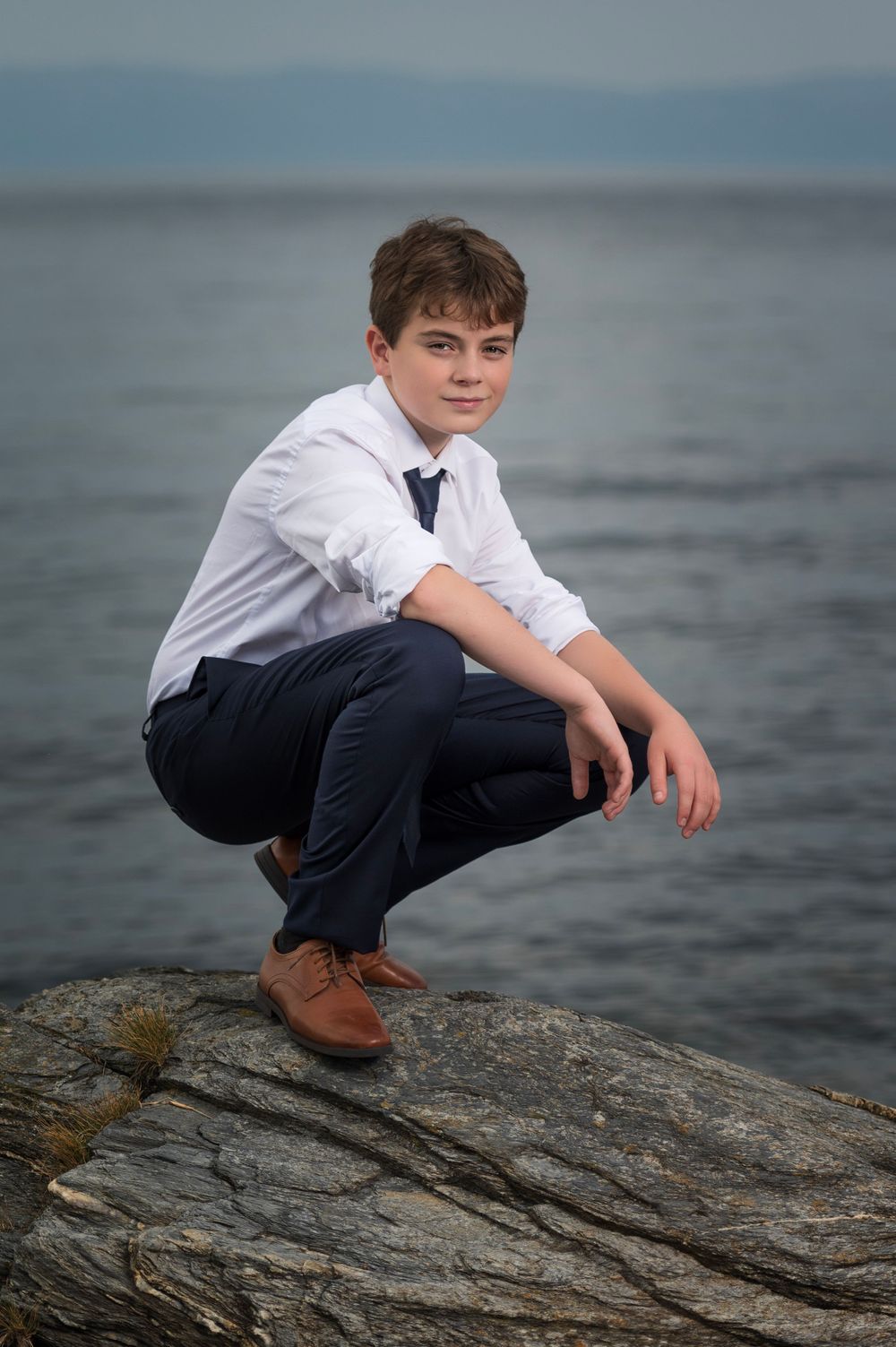 Formal attire portrait on rocky coastline in natural lighting.