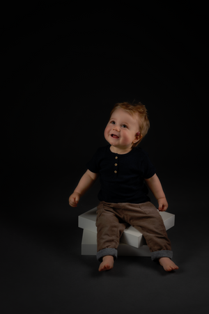 Studio portrait on black background showing playful poses in casual attire.