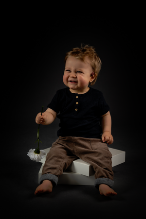 Low-key studio photography with dramatic lighting and white platform prop.
