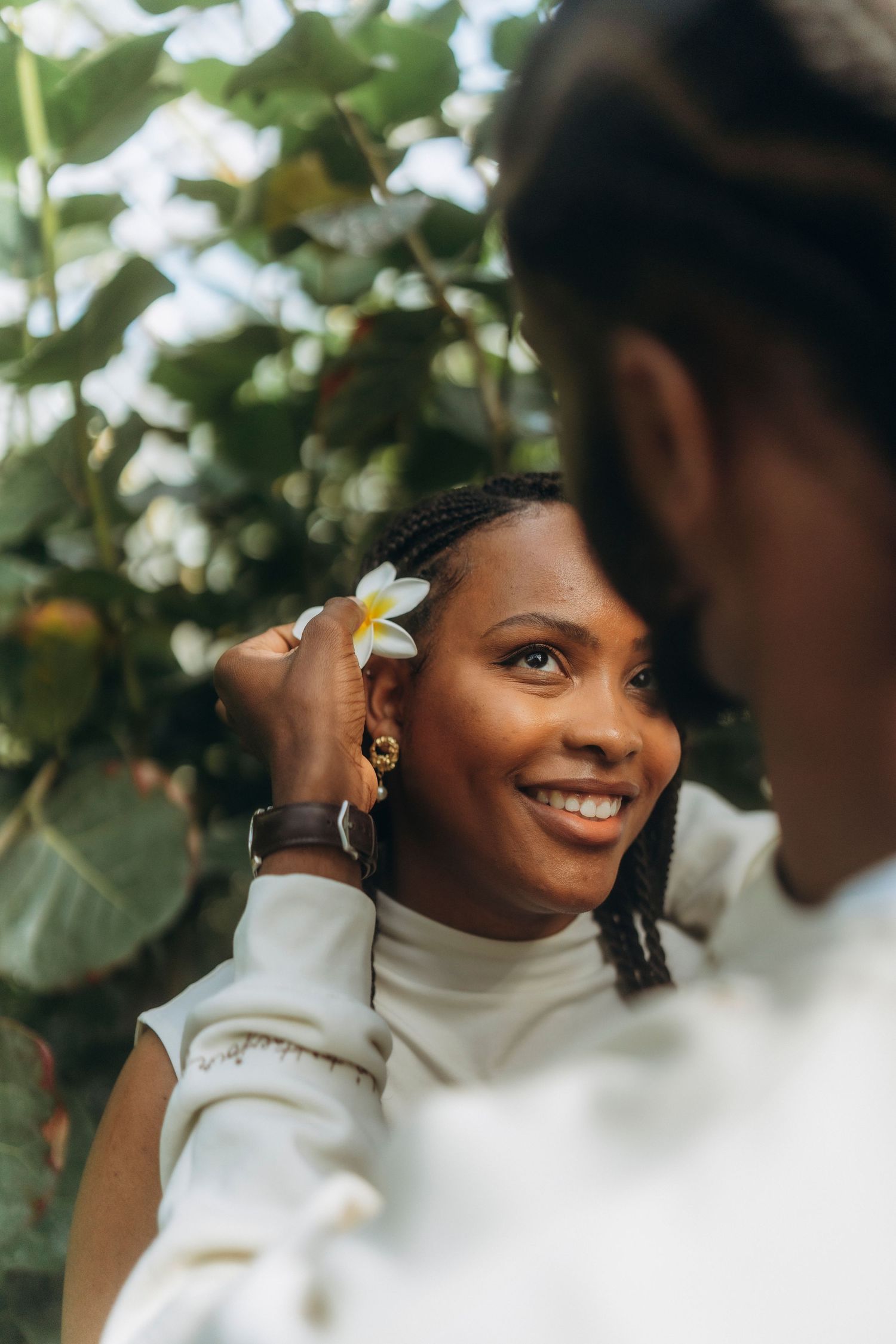 A tender moment captured as a white flower is placed in dark braided hair.