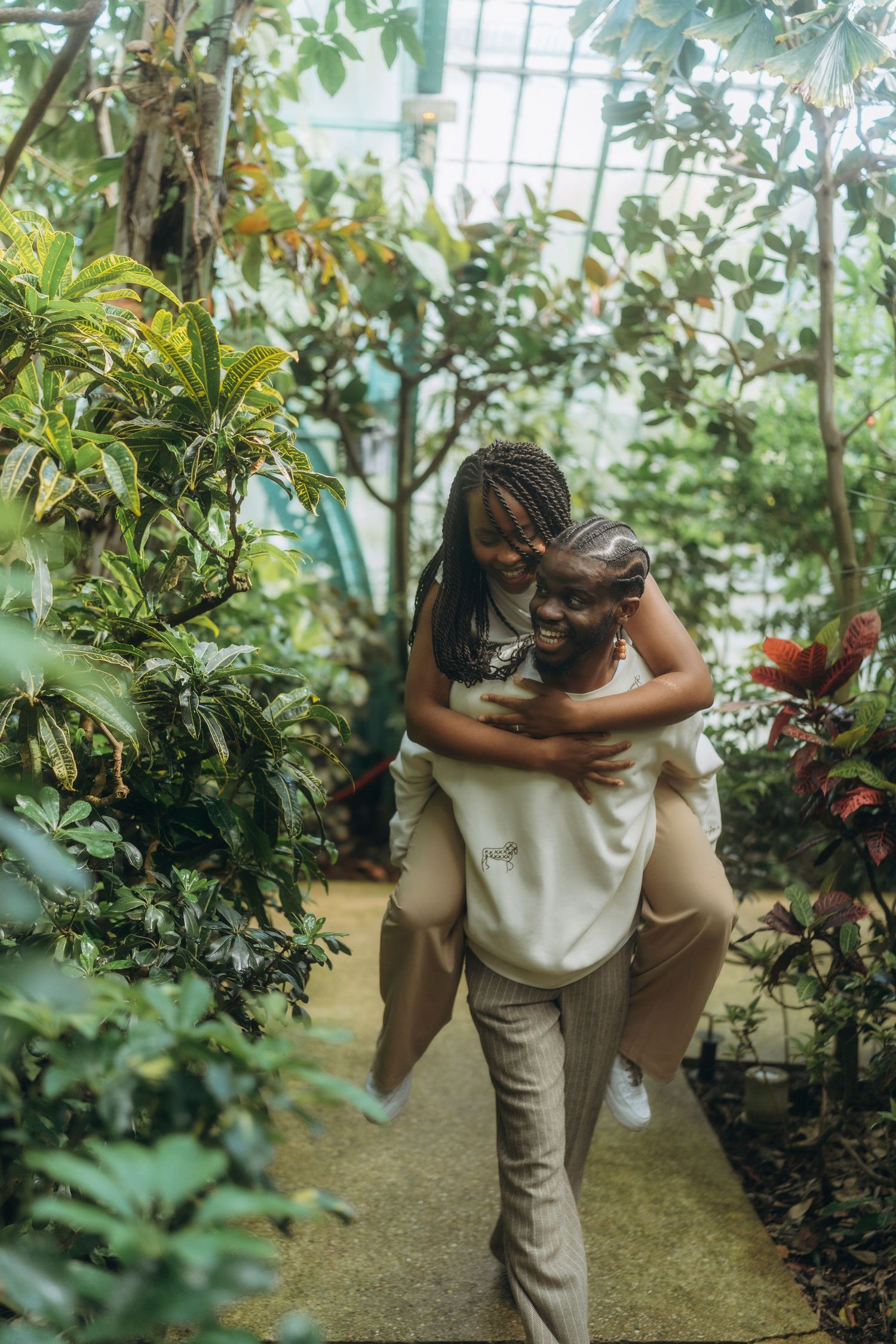 A piggyback ride through a lush greenhouse walkway filled with tropical plants.