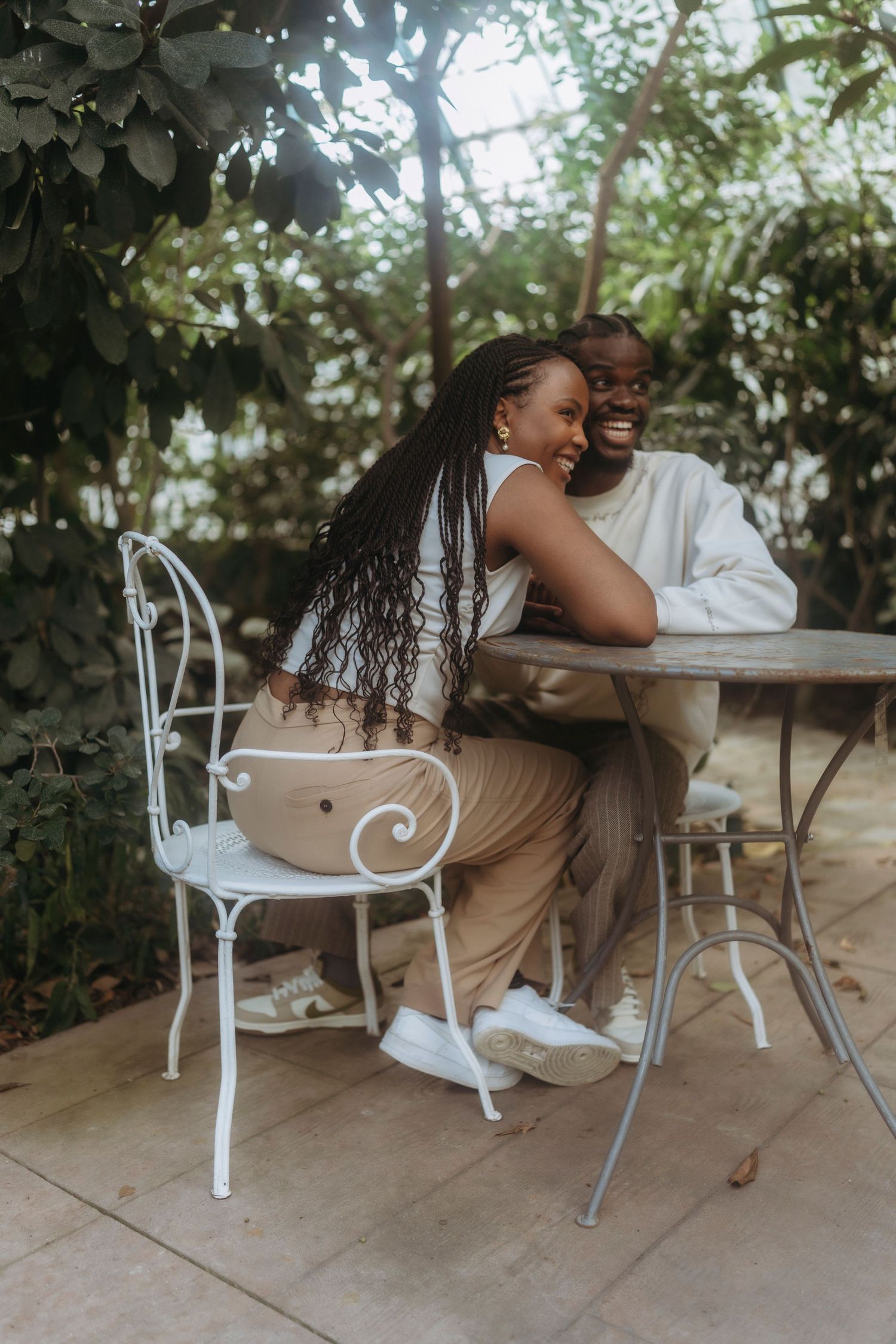 Couple enjoying a romantic moment while sitting at a cafe table in a garden setting.