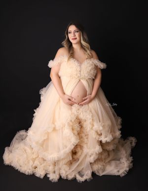 Elegant maternity portraits in flowing peach tulle gowns against black background.