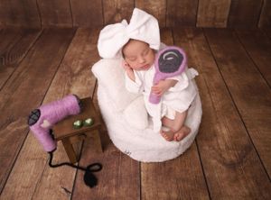 Creative newborn photo session with vintage sewing props and white dress.
