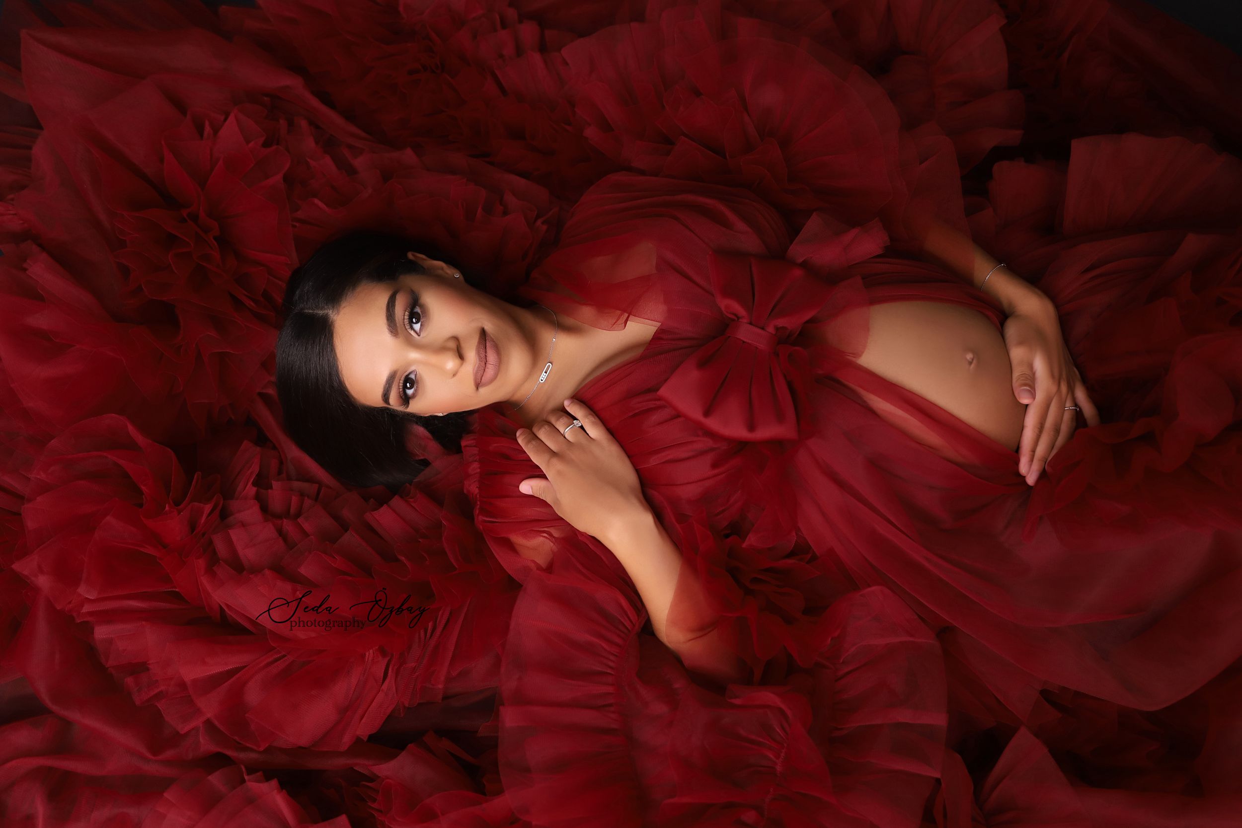 Dramatic red tulle gown flowing across dark backdrop in fashion photography.