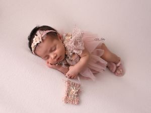 Artistic newborn photography with baby in pink tulle outfit on light background.
