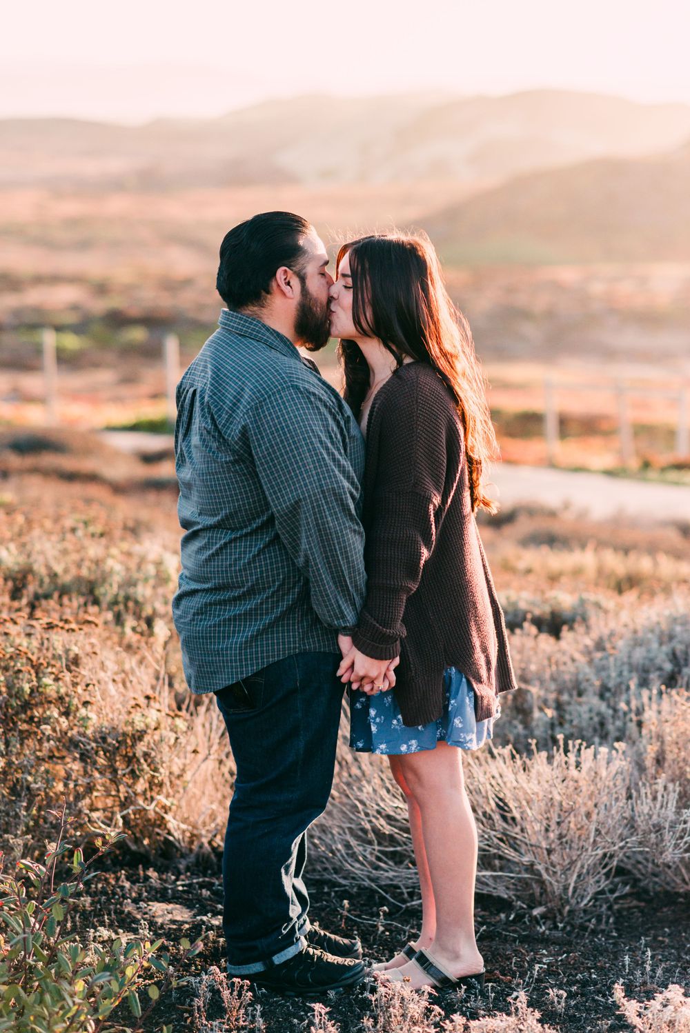 A romantic couple sharing an intimate moment against a mountainous backdrop at dusk.