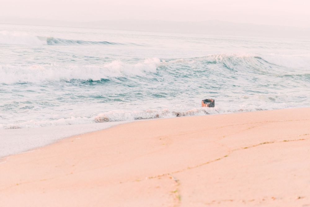 Soft waves rolling onto a pink-hued beach during sunset.