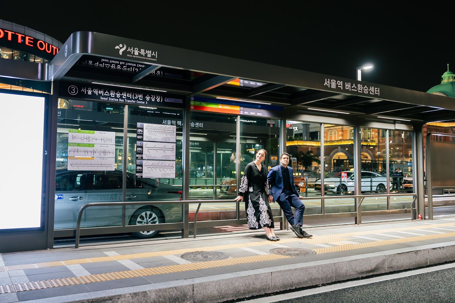 Modern subway platform in Seoul with illuminated signage and waiting passengers.
