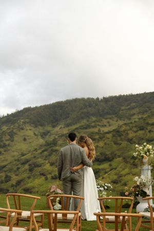 A couple overlooking a mountainous landscape at their outdoor wedding venue.
