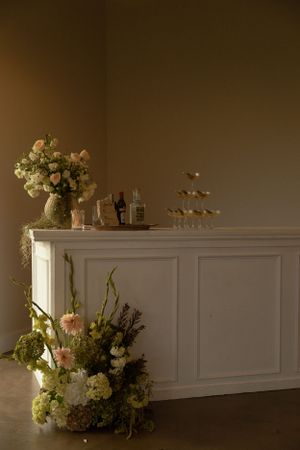 Elegant wedding bar setup with white floral arrangements and champagne display.