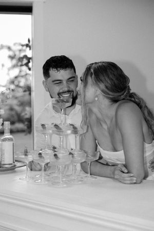 Candid moment of newlyweds sharing laughter at their wedding bar.