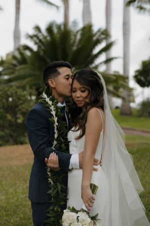 Romantic wedding moment captured under swaying palm trees at a tropical destination ceremony.