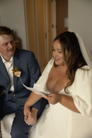 A couple reading letters together during their wedding day preparations.