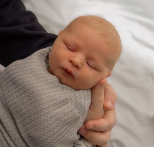 Sleeping newborn wrapped in soft gray textured blanket.