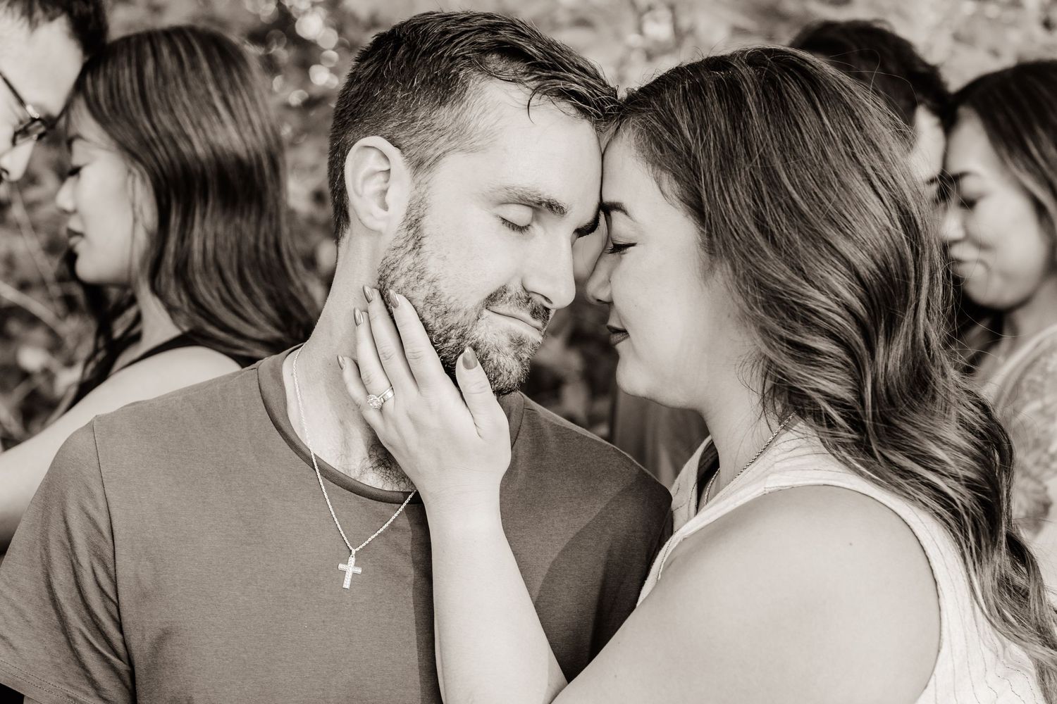 A tender black and white romantic moment between a couple as they share an intimate gesture outdoors.