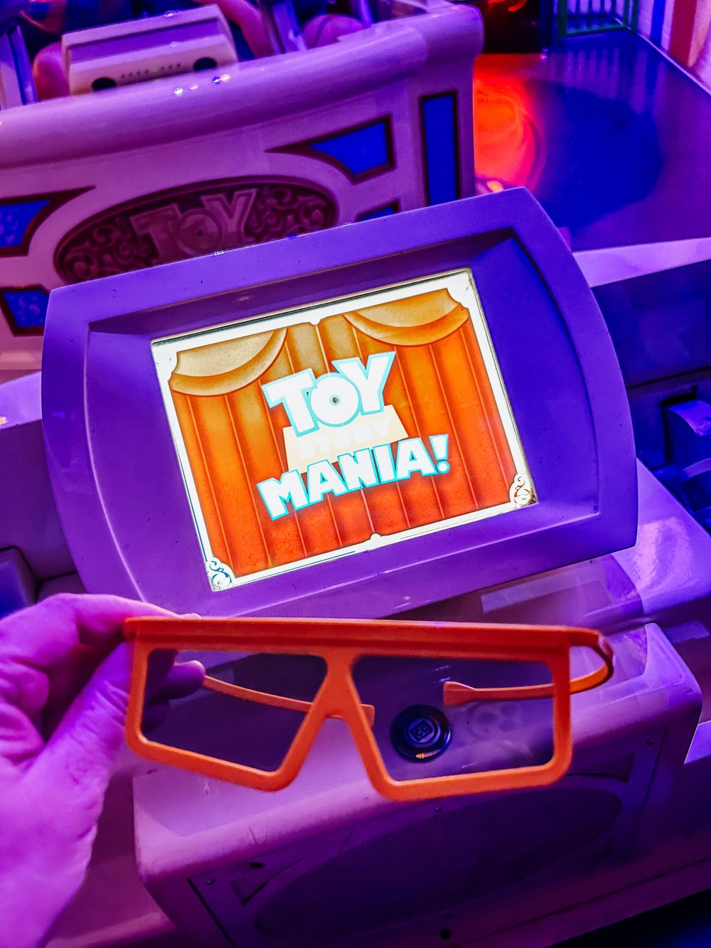 View of orange 3D glasses with TOHO MAX Cinema branding glowing under vibrant purple lighting.