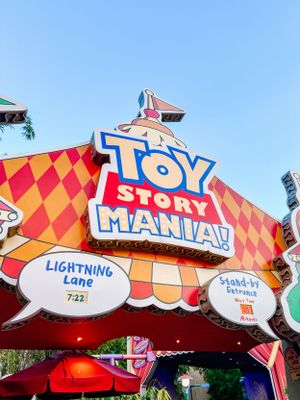 Colorful entrance sign for Toy Story Mania attraction with Lightning Lane display at Disney theme park.