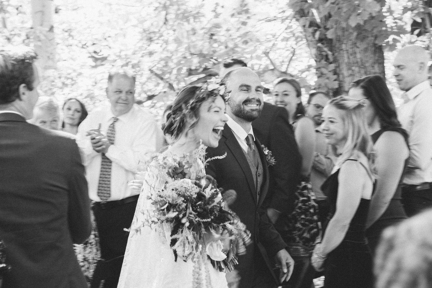 A joyful black and white wedding photo capturing a celebration with guests outdoors.