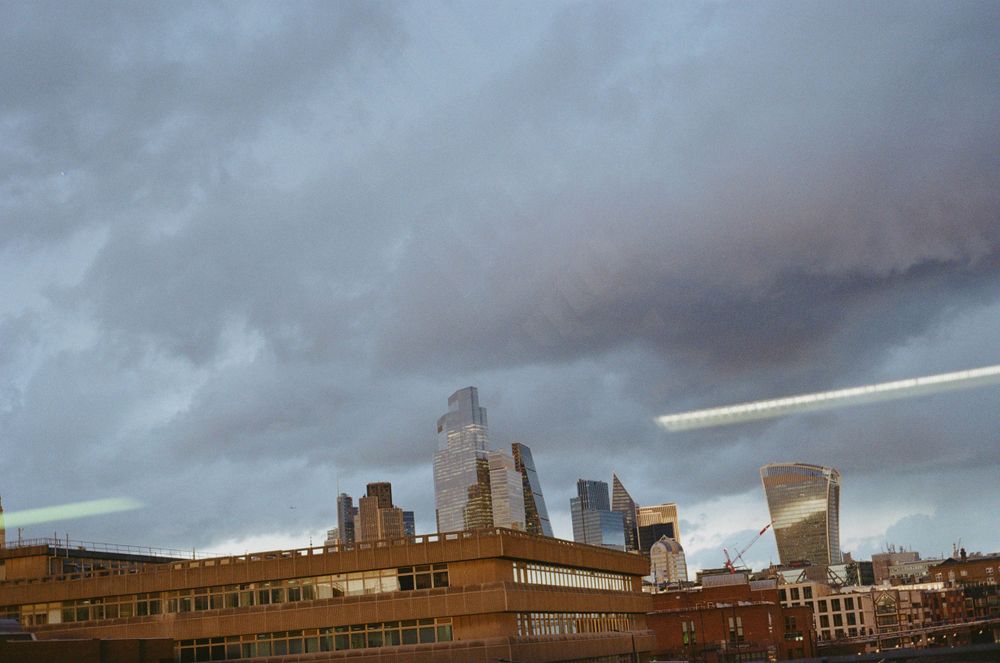Dramatic cloudy skyline of a city with tall buildings silhouetted against stormy skies.