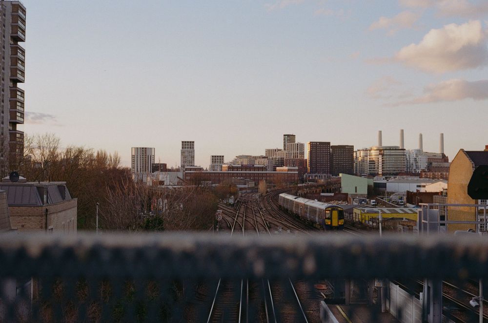 City skyline view across railway tracks at dusk showing modern buildings and industrial structures.