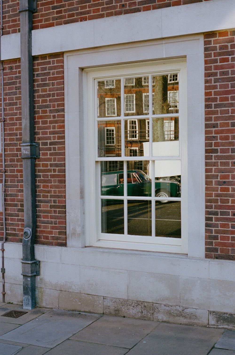 A traditional sash window in a brick building reflects neighboring Georgian architecture.