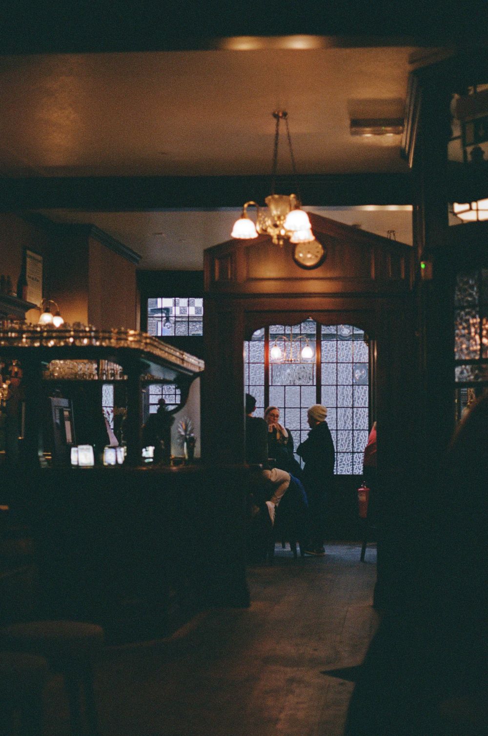 Moody interior of a traditional British pub with backlit windows and vintage lighting.