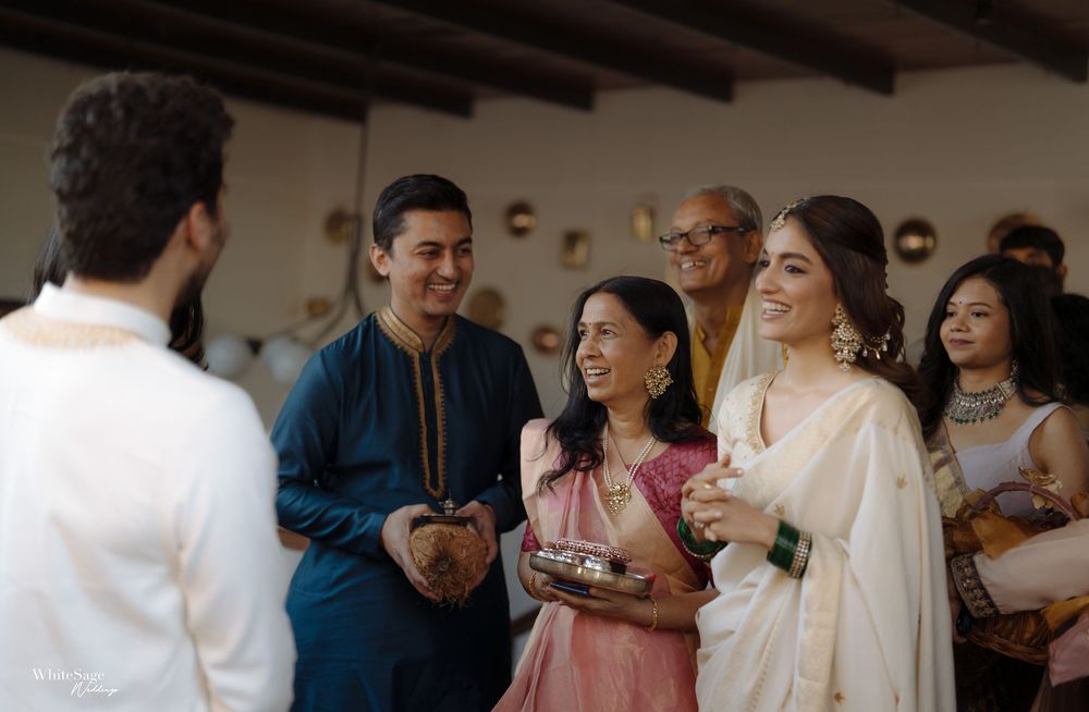 Guests in traditional Indian attire smiling and conversing at a festive celebration indoors.