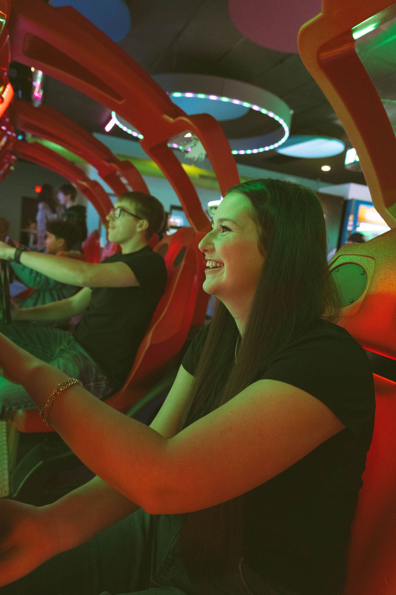 People enjoying an arcade or gaming experience with colorful neon lighting and excited expressions.