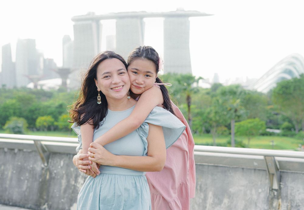 A tender embrace shared between two people with the iconic Marina Bay Sands hotel in Singapore visible in the background.