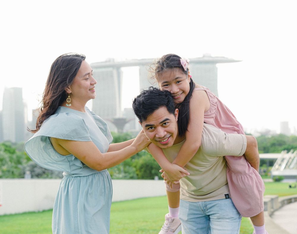 Happy family spending time together outdoors in a park with city skyline in background.