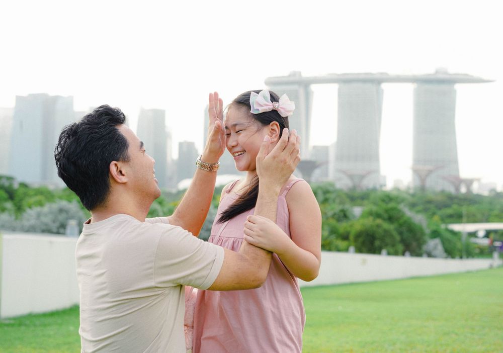 Sweet couple share an intimate romantic moment on a rooftop garden with Singapore's Marina Bay Sands skyline in background.