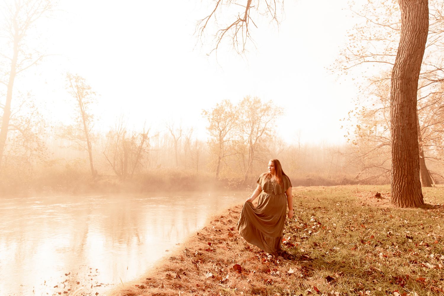 Silhouette figure in vintage sepia tones sits peacefully by misty lake at dawn with bare trees in background.