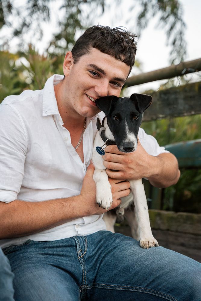 A young man holding his fox terrier during a dog friendly family photoshoot in the central coast NSW