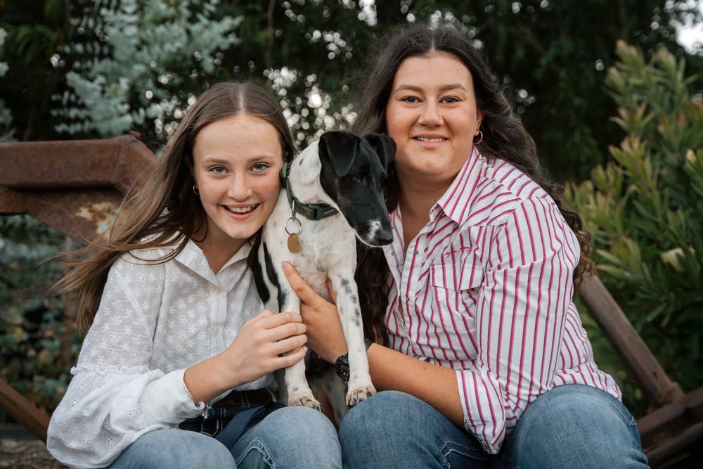 sisters holding their cute fox terrier during a rural family photoshoot in the central coast