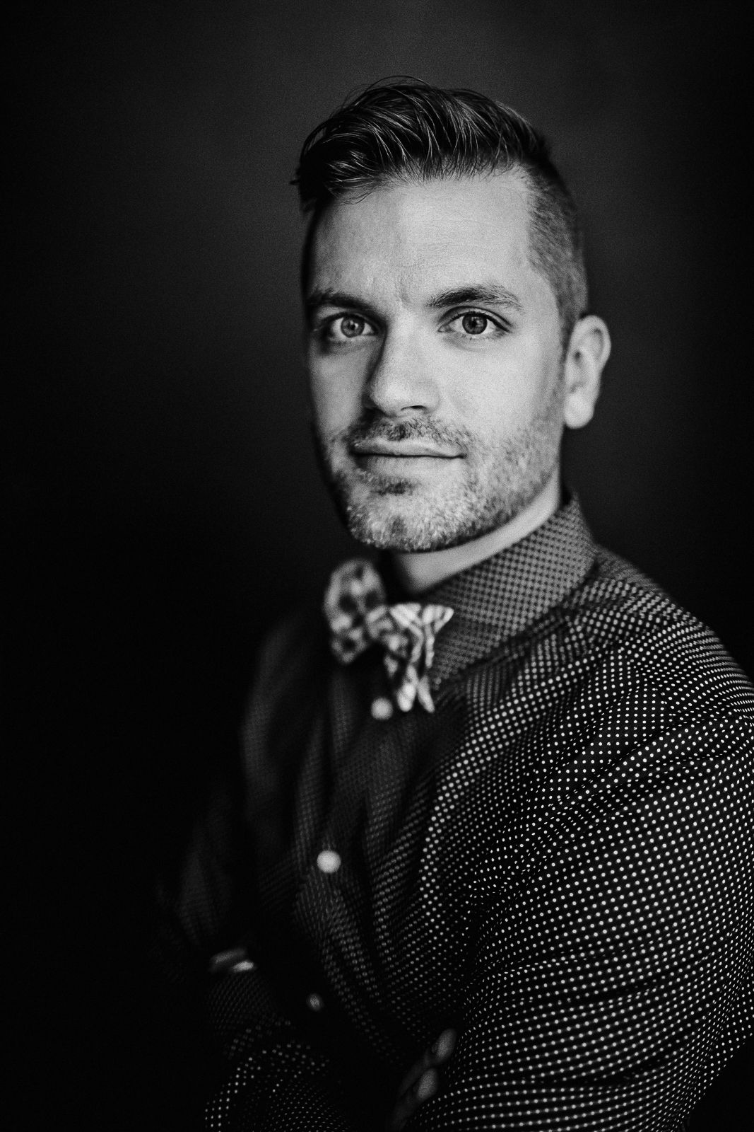 Black and white studio portrait showing elegant attire with bow tie and patterned shirt.