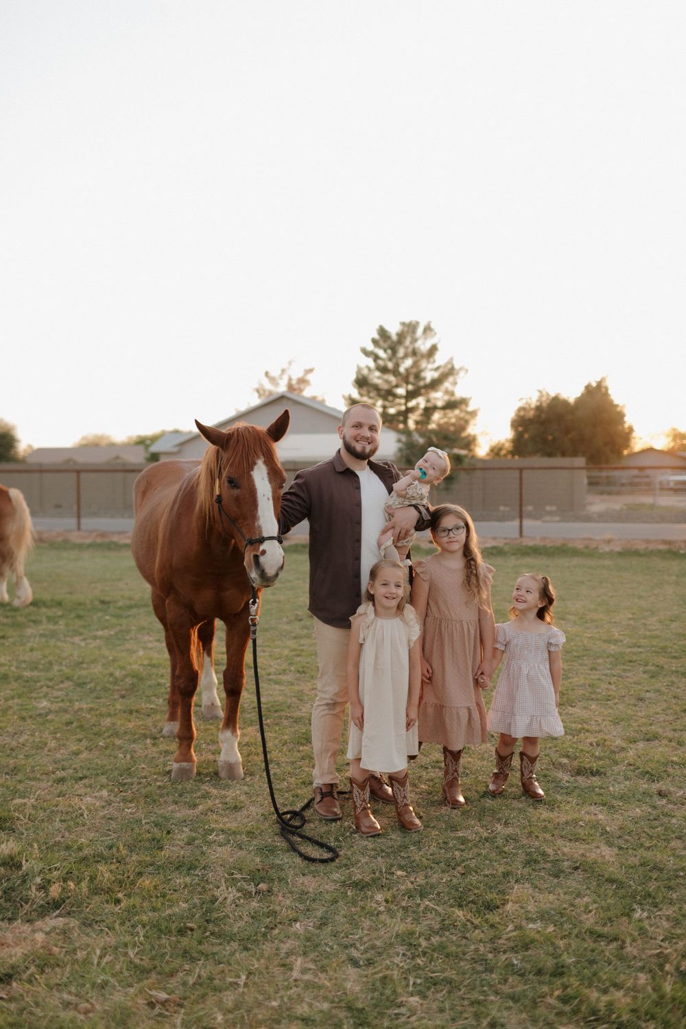 Family poses with their brown horse in a field during golden hour.