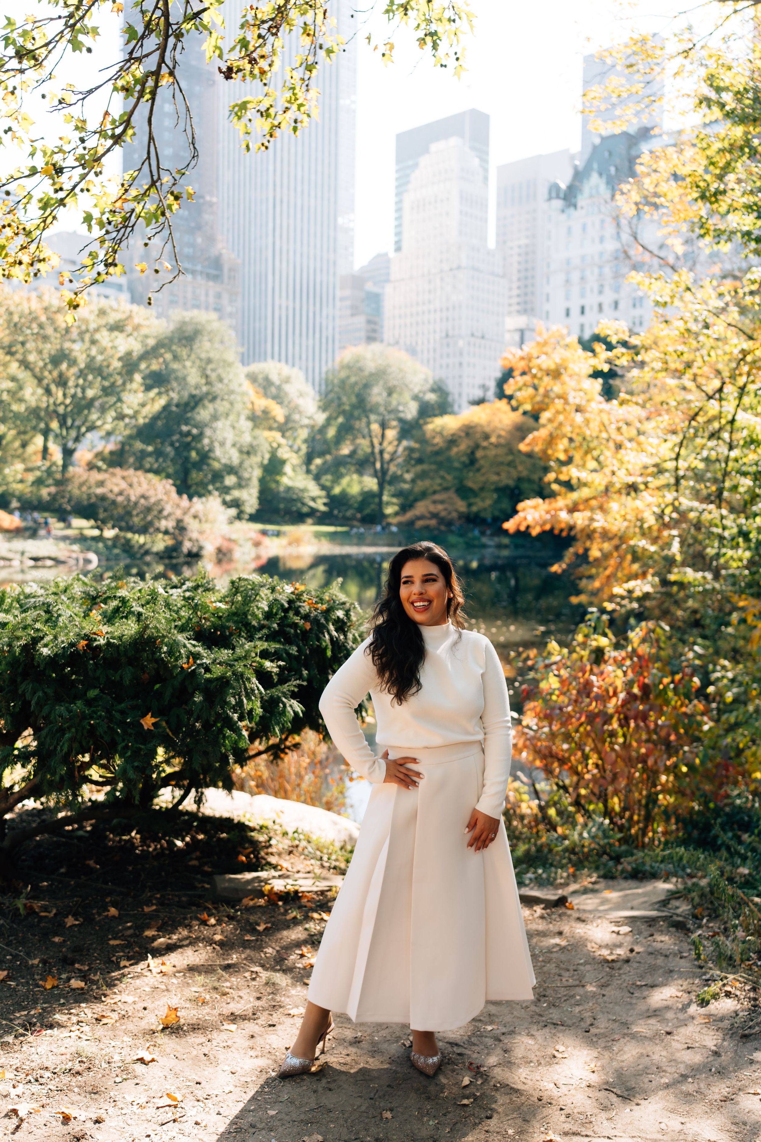 Scenic autumn view in Central Park with tall Manhattan skyscrapers in background on sunny fall day.