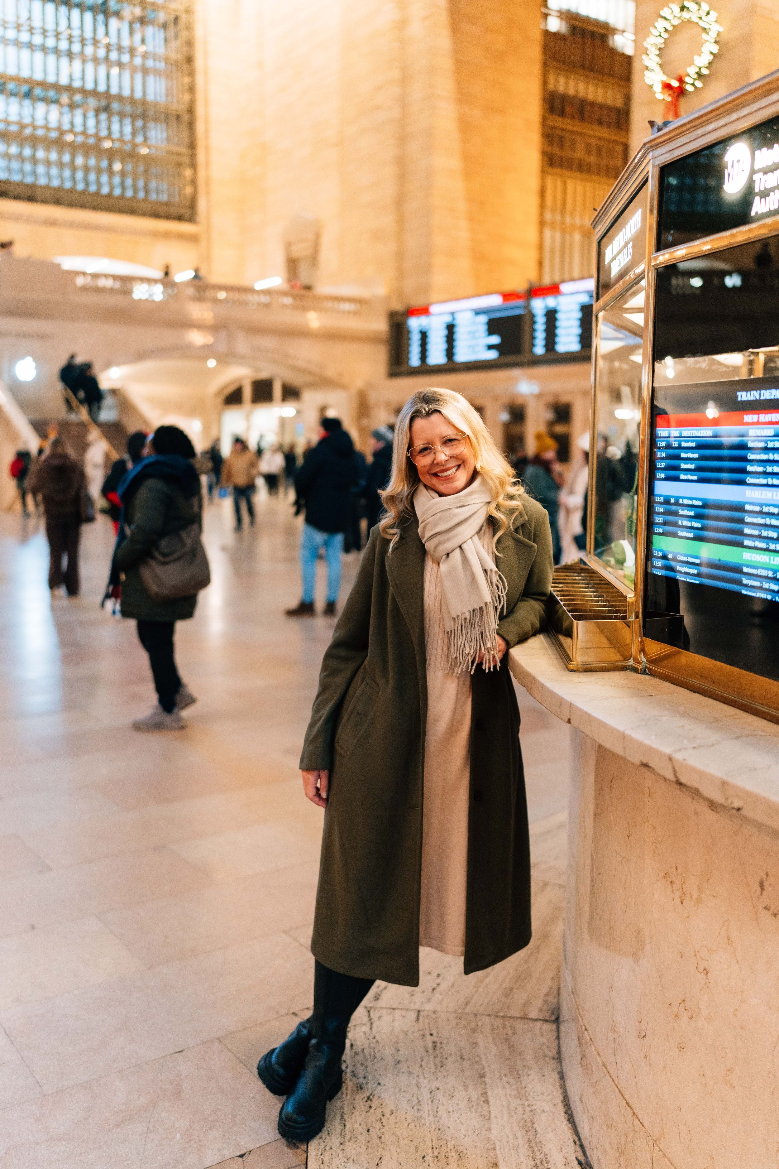 Inside the historic Grand Central Terminal, a person in winter attire stands by a departure board in the bustling main concourse.