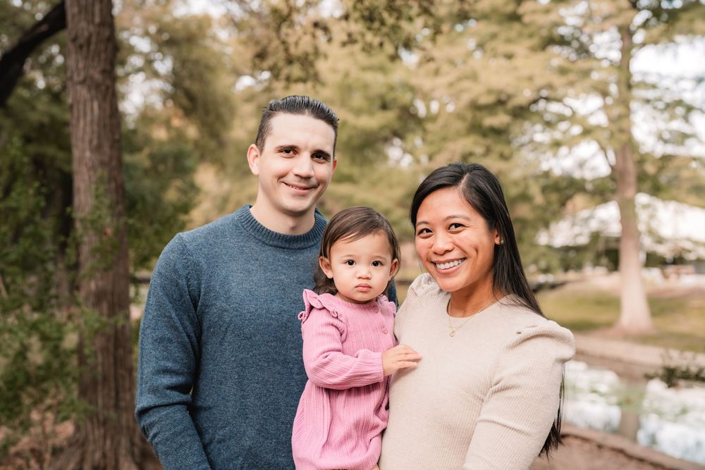 Family enjoying a warm autumn day together outdoors in a park with trees and natural lighting.