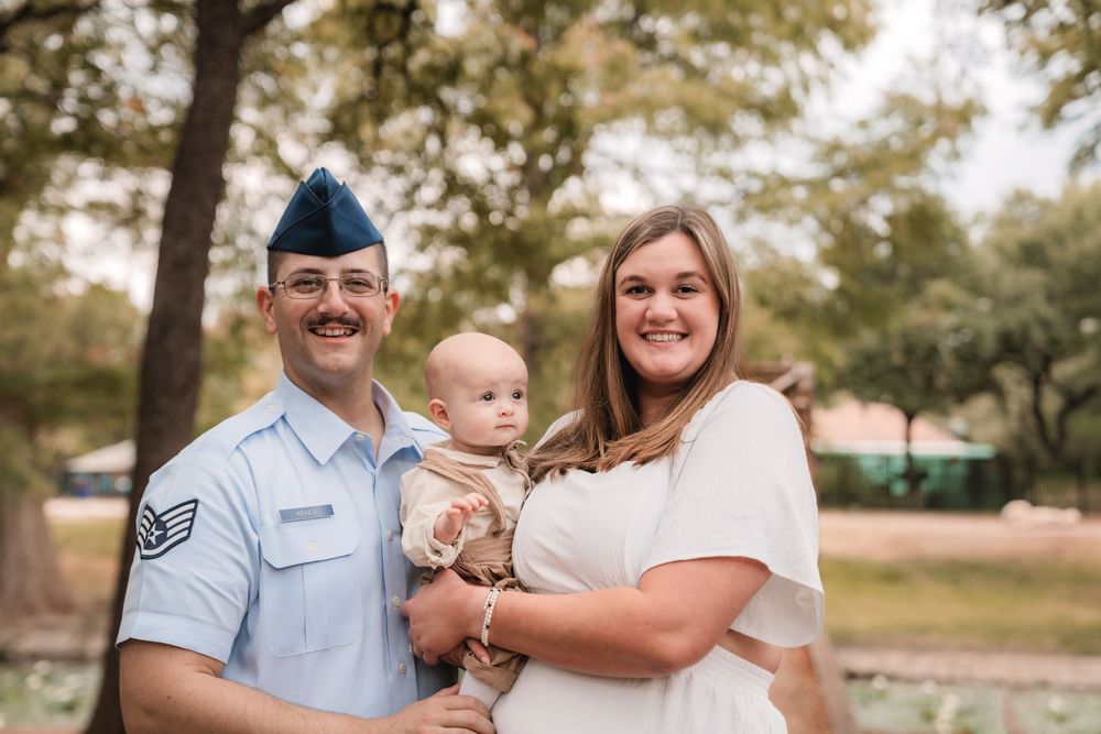 A happy military family poses together outdoors during a golden sunset photo session.