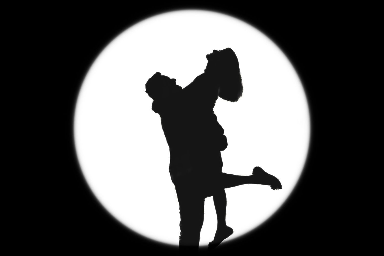 Silhouette of a couple in a romantic embrace against a glowing moon backdrop, symbolizing love and connection. Perfect for wedding